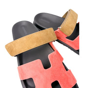 An overhead, staggered perspective of the luxury Hermès sandals, emphasizing the precision stitching along the iconic H-shaped leather cutout.