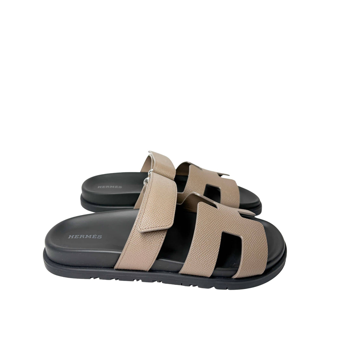 Direct level side view of a single Hermès Chypre sandal, showing the low-profile 1.2 cm black rubber sole and sleek contours