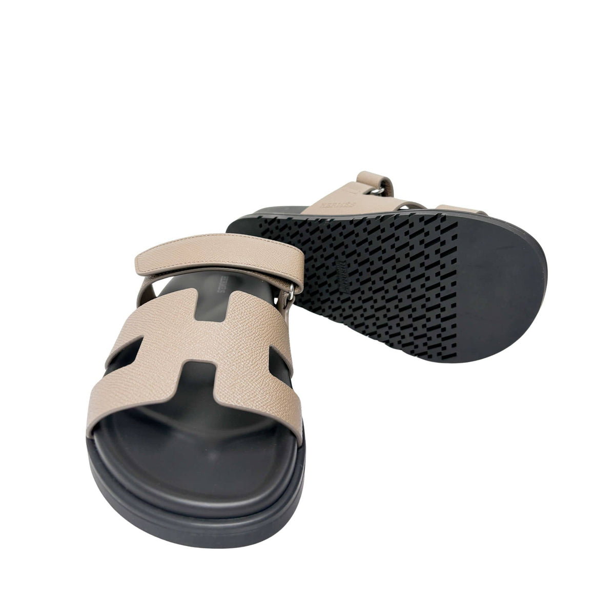 Rear angle view of the Hermès Chypre leather sandal from behind, focusing on the structured heel cup and textured rubber outsole edge.