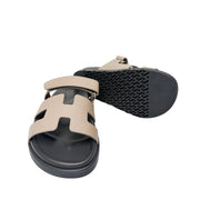 Rear angle view of the Hermès Chypre leather sandal from behind, focusing on the structured heel cup and textured rubber outsole edge.