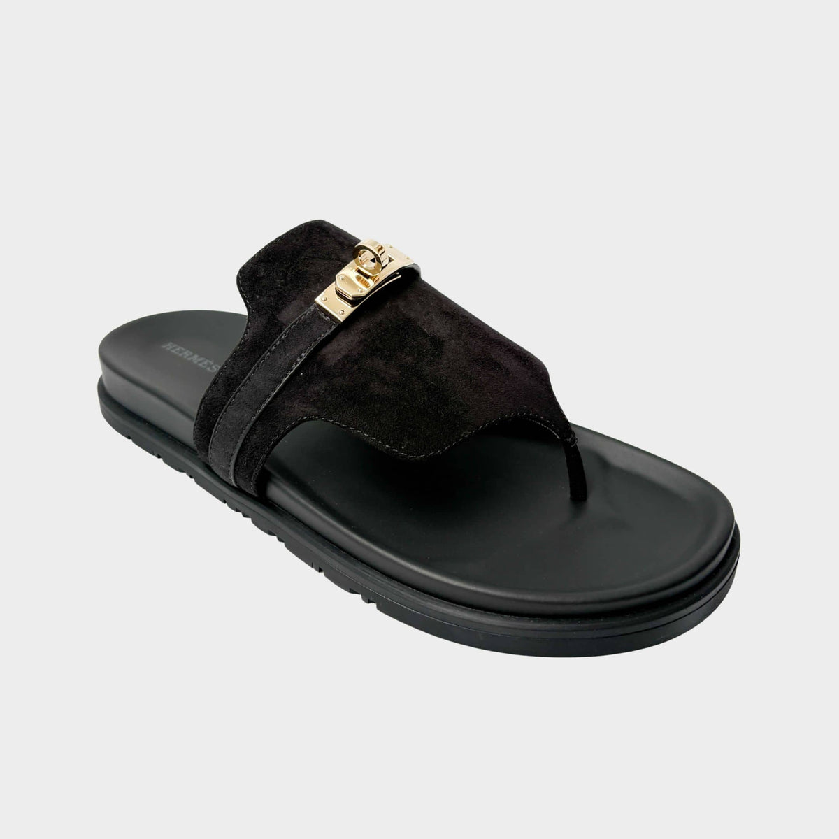 A side profile view of the Hermès Chypre sandal showcasing the bold contrast between its vibrant coral-red leather upper and the thick black rubber sole.