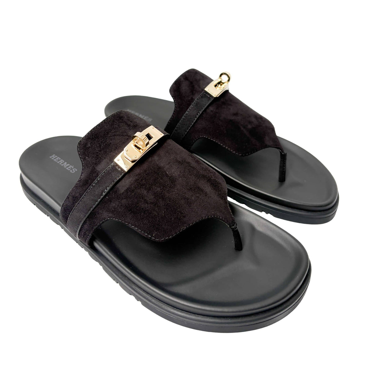 Symmetrical studio shot of both Hermès Chypre sandals side-by-side, highlighting the signature anatomical black calfskin footbeds and open toe design.