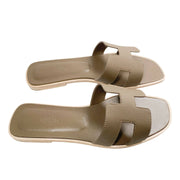 A direct glance at the inner footbeds of the flat Hermès summer slides, showcasing the branded luxury stamping and the ergonomic curvature made for daily wear