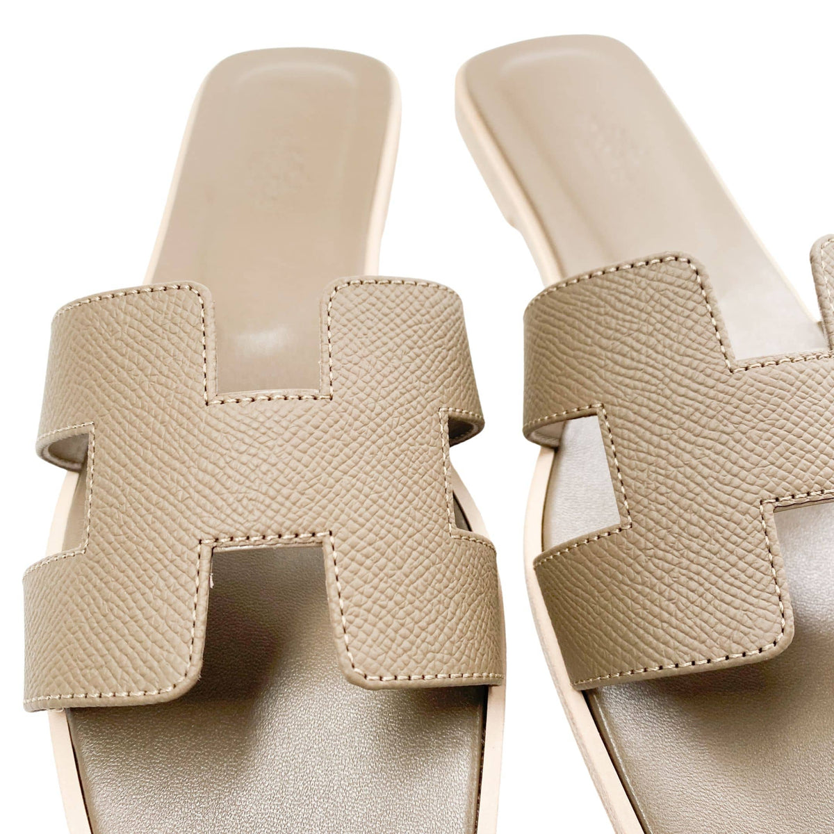 A unique overhead perspective looking straight down onto the open heel entry of the Oran sandals, drawing focus to the smooth texture of the neutral taupe leather lining.