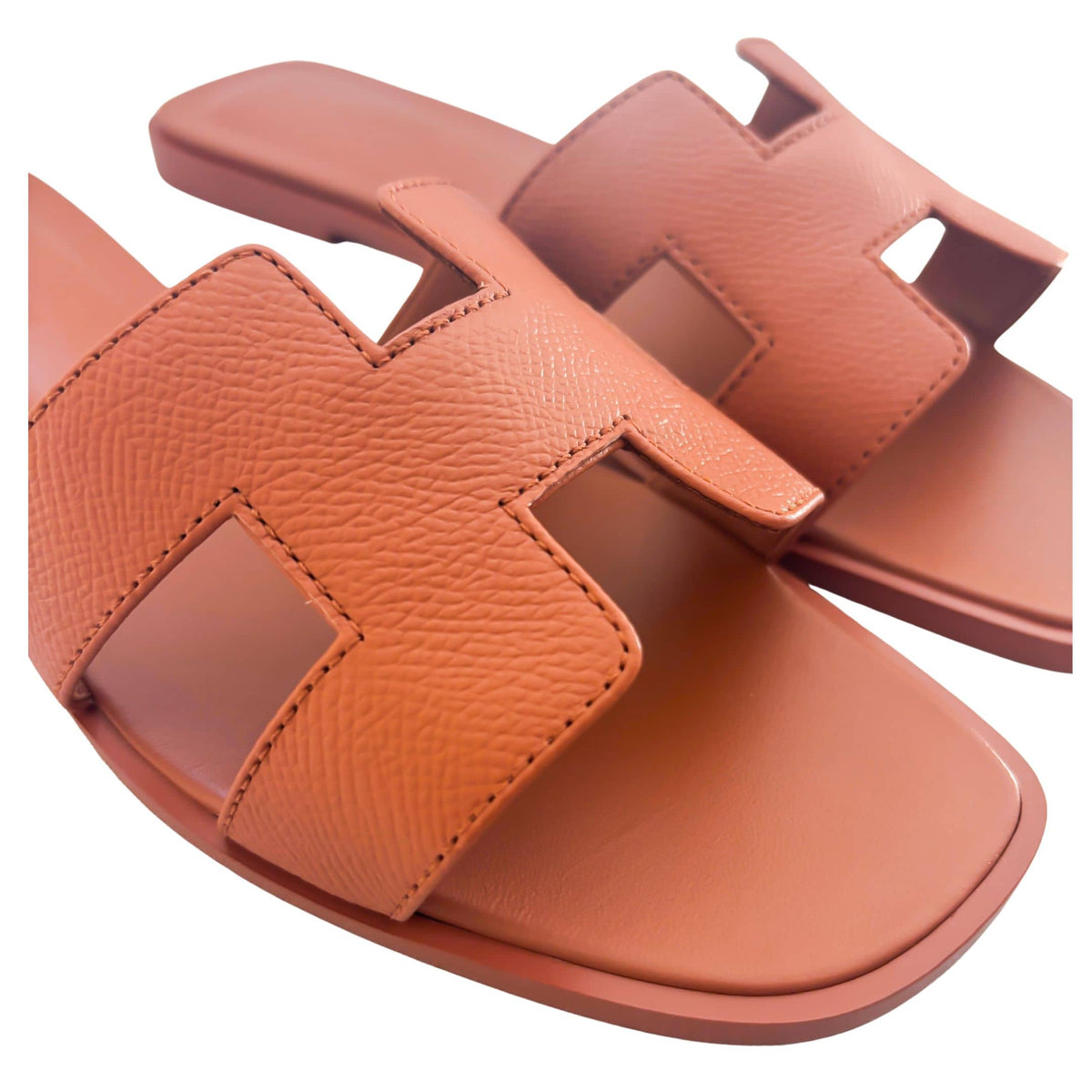 A close-up, angled look at the luxury slip-on slides, capturing the fine grain of the Orange Canyon calfskin leather under studio lighting.