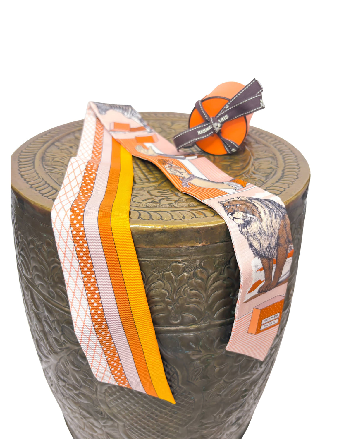 Side angle display of Hermès Grand Théâtre Nouveau silk Twilly scarf wrapped around a textured pedestal