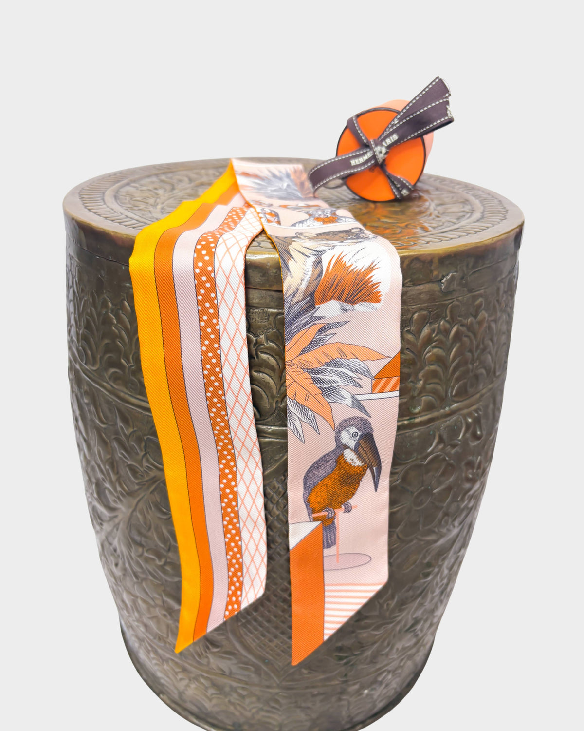 Hermès Grand Théâtre Nouveau silk Twilly scarf in poudre pink and vibrant orange styled over a decorative stand