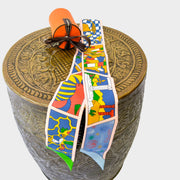 Authentic Hermès Twilly Factory Sweet silk scarf in Blue, Rose, and Mordori, styled elegantly on a display stand.