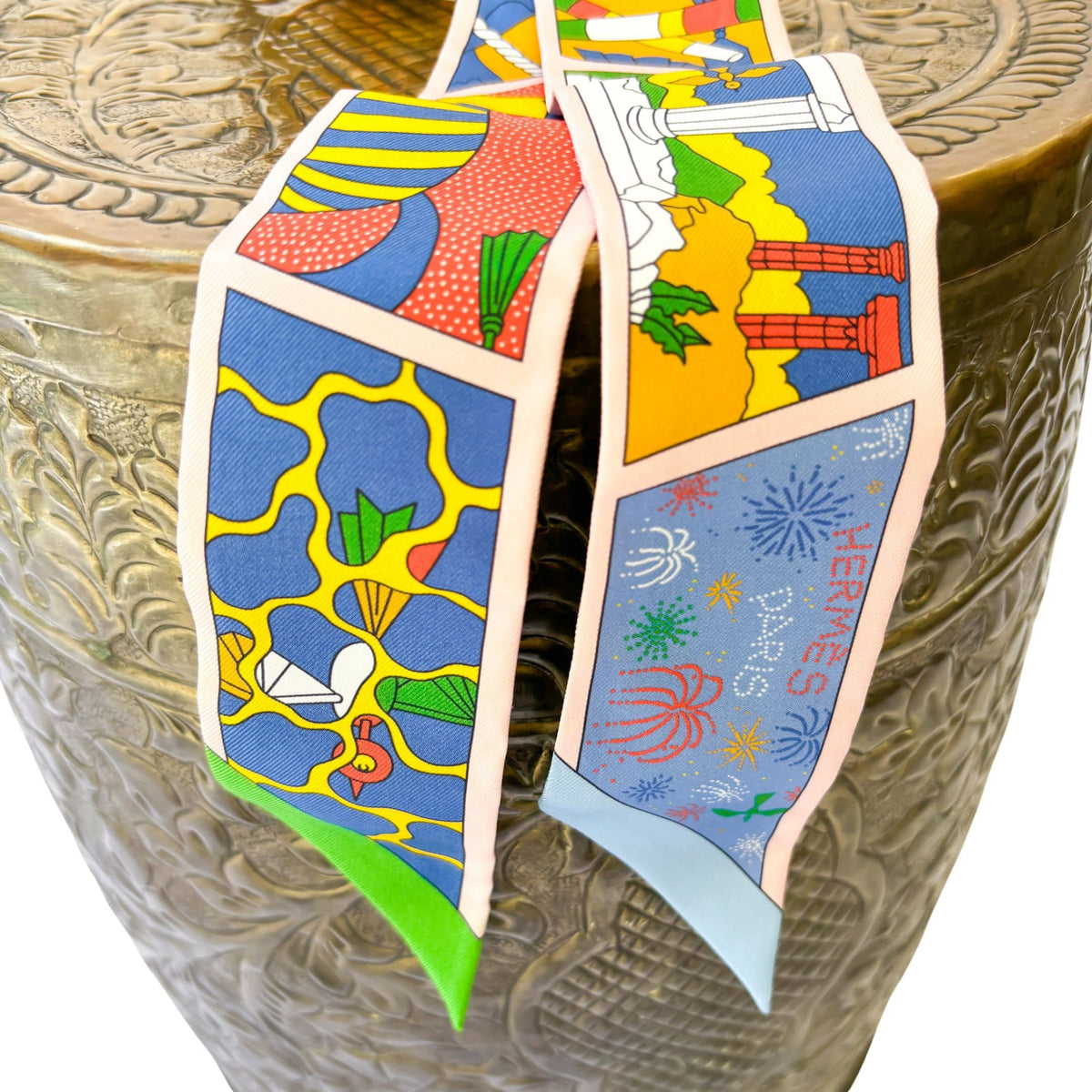 Close-up view of the playful Factory Sweet motif on a multi-color Hermès silk Twilly scarf.