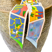 Close-up view of the playful Factory Sweet motif on a multi-color Hermès silk Twilly scarf.
