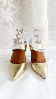 Direct front view of Jimmy Choo Cheri 85 gold metallic pumps on foot highlighting the sleek pointed toe box.