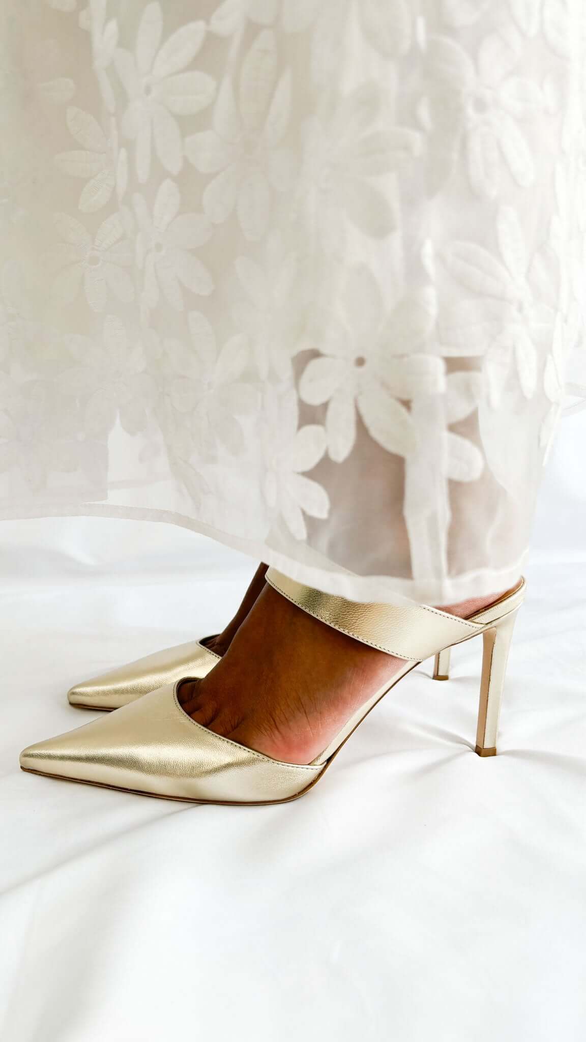 Side profile view of Jimmy Choo Cheri 85 metallic gold leather heels worn on foot showcasing the flattering ankle cuff.
