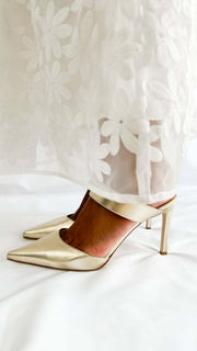 Side profile view of Jimmy Choo Cheri 85 metallic gold leather heels worn on foot showcasing the flattering ankle cuff.