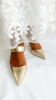 Front view of Jimmy Choo Cheri 85 metallic gold heels styled on foot with a white lace wedding dress.