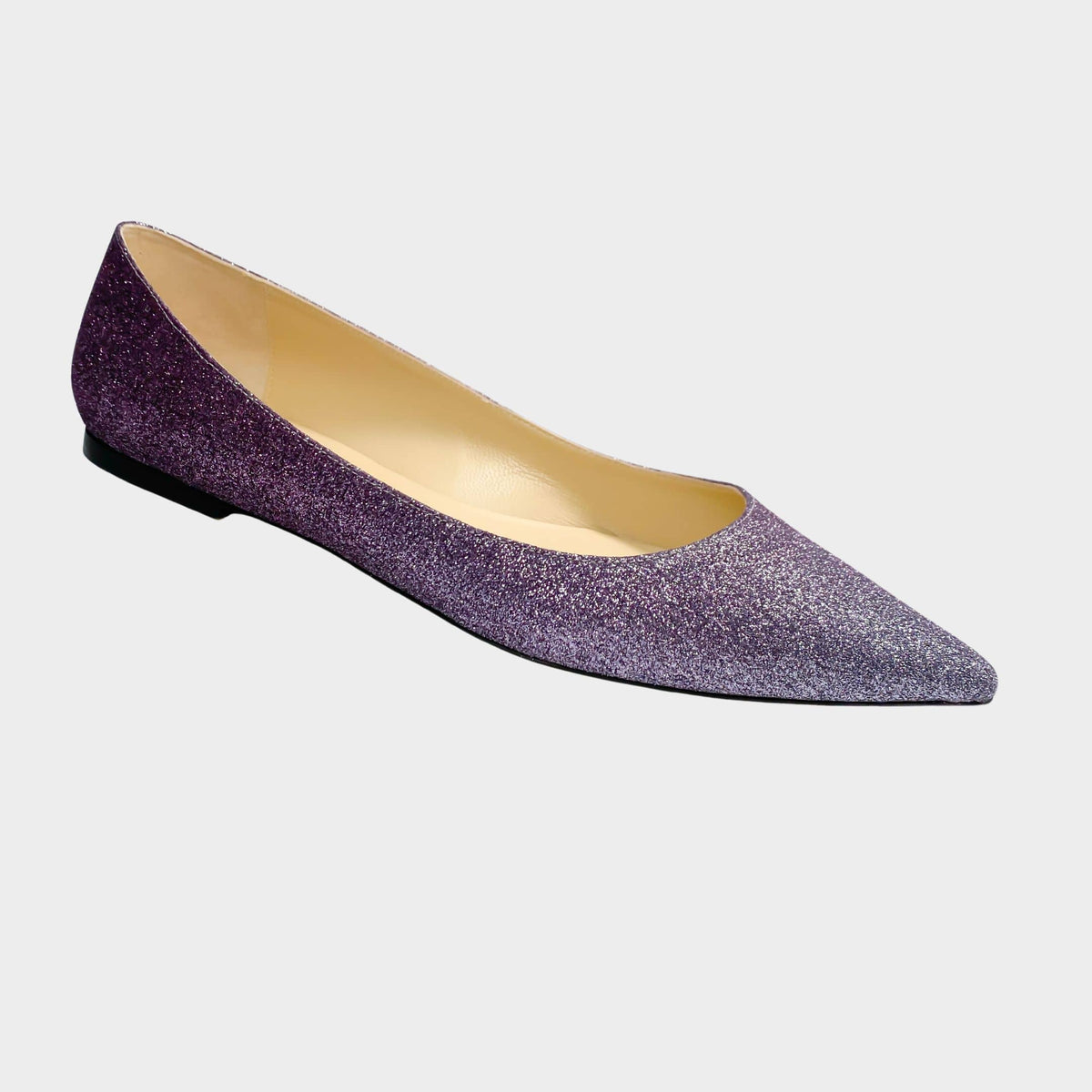 An elegant side profile view of a single Jimmy Choo Alina flat, capturing the striking ombré shift from a rich plum hue at the toe into a glittering metallic gunmetal heel.