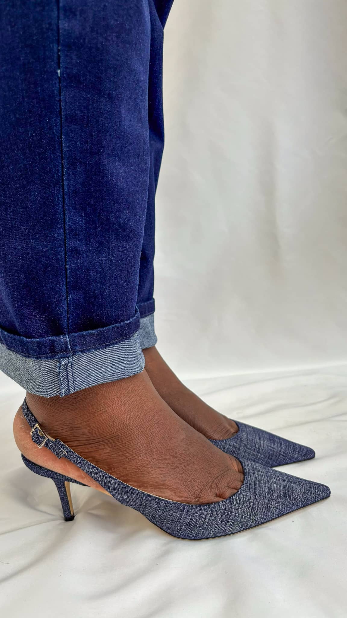 Rear view on foot showcasing the slim slingback ankle strap and heel counter of the Jimmy Choo Harper denim pump.