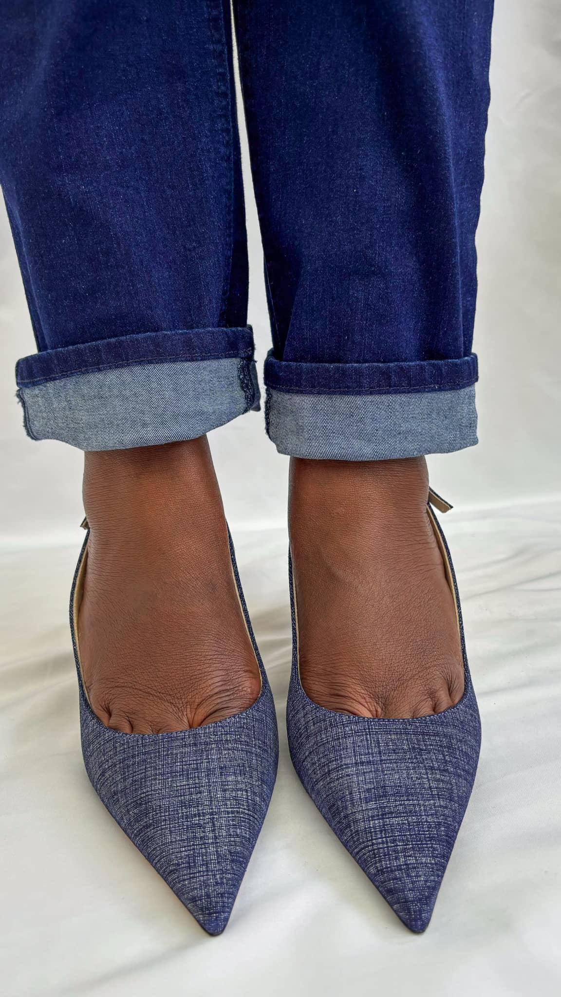 Direct front view of Jimmy Choo Harper 65 denim kitten heels styled on foot with cuffed jeans.