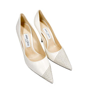 Direct front view of a pair of Jimmy Choo Love 100 pointed-toe off-white leather bridal pumps with silver studs.