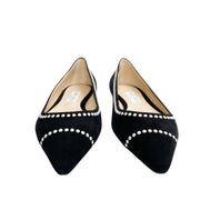 Direct front view of a pair of Jimmy Choo Romy pointed-toe flats in black suede highlighted by white pearl detailing.