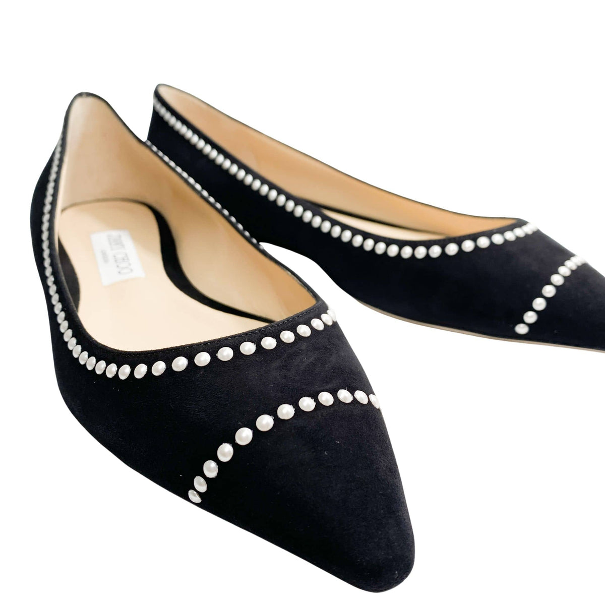 Angled perspective shot of Jimmy Choo Romy black suede pointed flats with pearl border accents.
