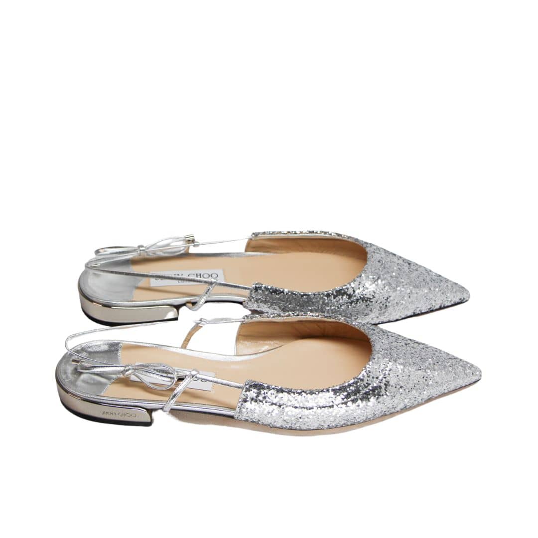 Side view of Jimmy Choo Gemista silver flats showcasing the elastic slingback strap, low flat heel, and metallic sparkle fabric.