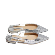Side view of Jimmy Choo Gemista silver flats showcasing the elastic slingback strap, low flat heel, and metallic sparkle fabric.