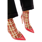Jimmy Choo Sheldon 100 red leather cutout bootie heels styled on foot with dark trousers.