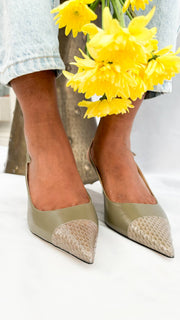 An on-foot studio perspective of the green leather Jimmy Choo heels, paired with light-wash denim to demonstrate a sophisticated casual look.