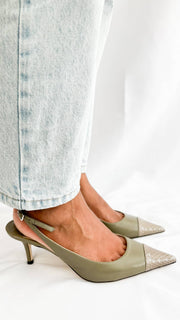 A side-angle on-foot view of the luxury kitten heels, beautifully capturing the subtle sheen of the smooth olive leather under bright studio lighting.
