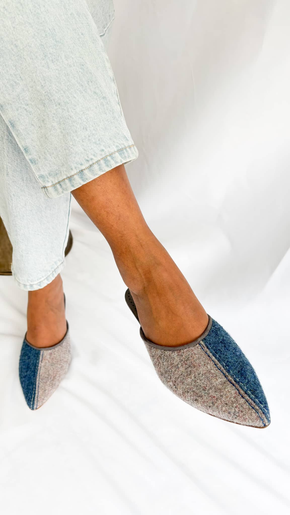 Standing on-foot view of Manolo Blahnik Ajita 30 grey and blue wool felt kitten heel mules worn with relaxed denim.