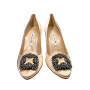 Studio side profile of Manolo Blahnik Hangisi 105 champagne satin pump showing the elegant heel curve and jewel buckle.