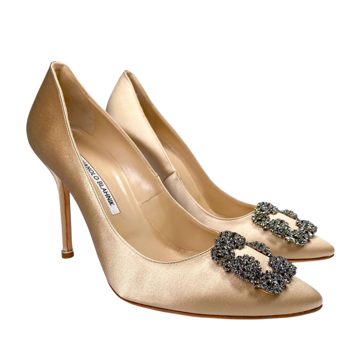 Three-quarter studio view of a pair of Manolo Blahnik Hangisi 105 champagne satin luxury bridal pumps.