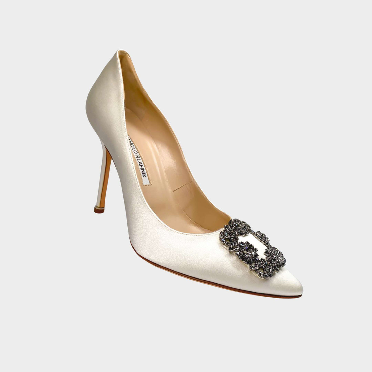 Manolo Blahnik Hangisi 105 white satin pumps featuring the iconic square crystal buckle encased in a gunmetal frame.