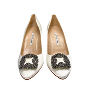 Top-down studio view of the Manolo Blahnik Hangisi white satin pumps showing the beige leather lining and insoles.