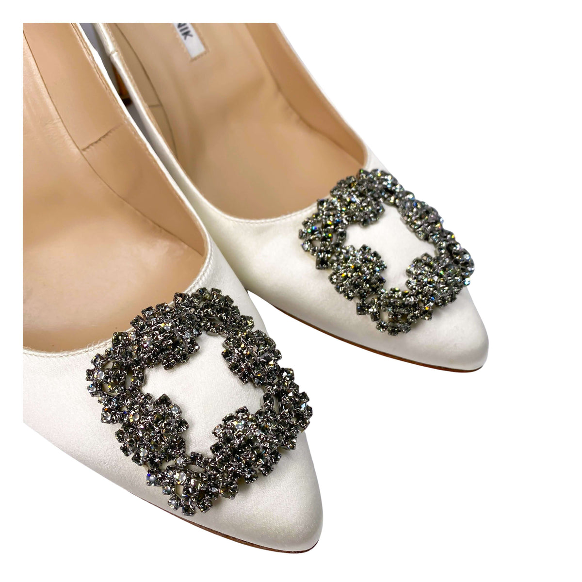 Close-up detail of the brilliant square crystal embellishment on the white silk-satin upper of a Manolo Blahnik pump.