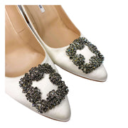 Close-up detail of the brilliant square crystal embellishment on the white silk-satin upper of a Manolo Blahnik pump.