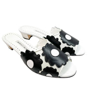 Three-quarter studio view of a pair of Manolo Blahnik Lottara 30 black and white floral cutout leather slide sandals.