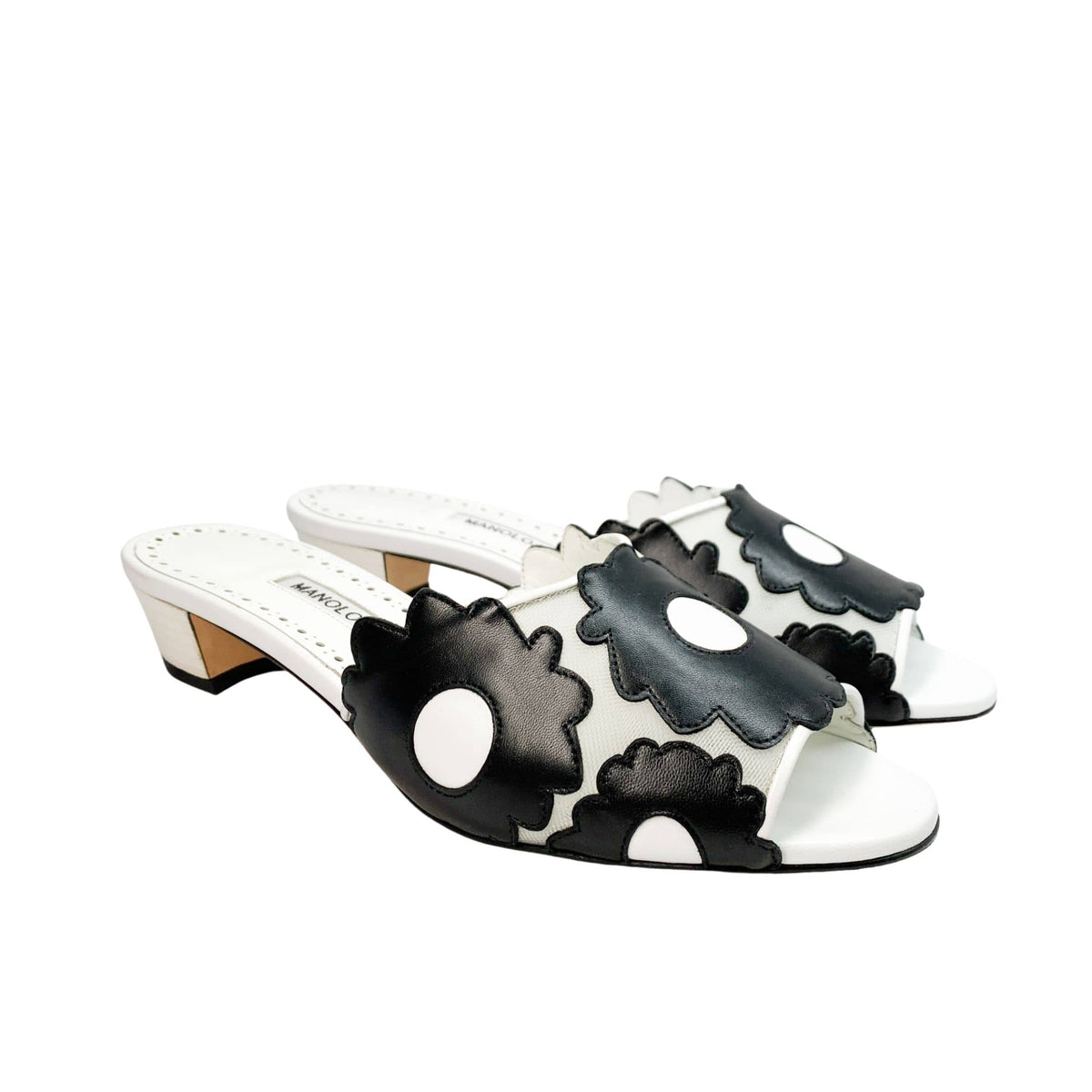 Three-quarter side angle view of Manolo Blahnik Lottara 30 low heel slide sandals showing the black flower appliques and white leather footbed.