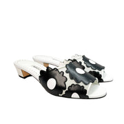 Three-quarter side angle view of Manolo Blahnik Lottara 30 low heel slide sandals showing the black flower appliques and white leather footbed.