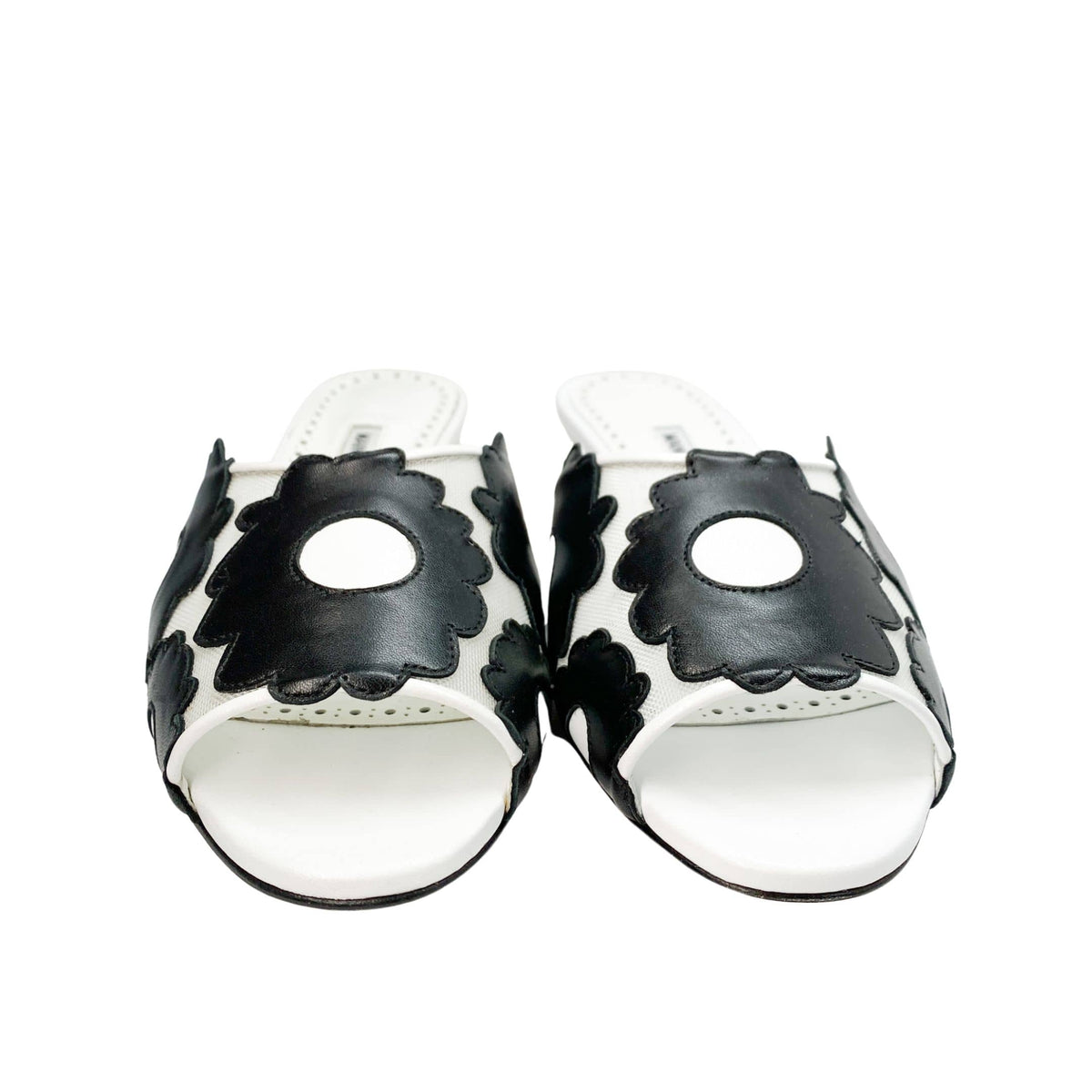 Direct front view of a pair of Manolo Blahnik Lottara 30 open-toe sandals displaying the black and white floral cutout strap design.