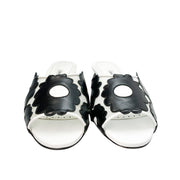 Direct front view of a pair of Manolo Blahnik Lottara 30 open-toe sandals displaying the black and white floral cutout strap design.