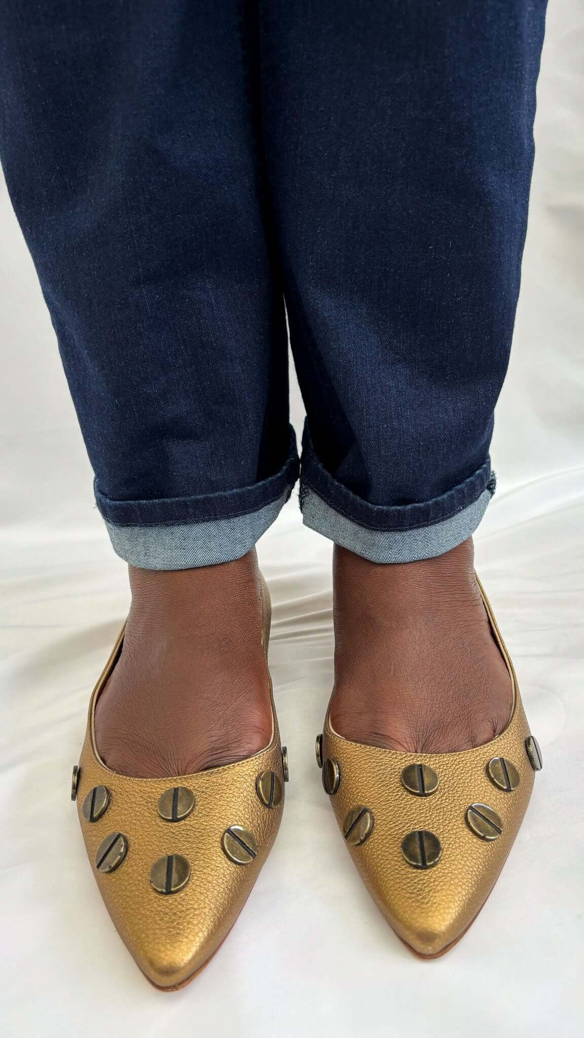 Front view of Manolo Blahnik Panunzia bronze leather flats styled on-foot with casual denim jeans.