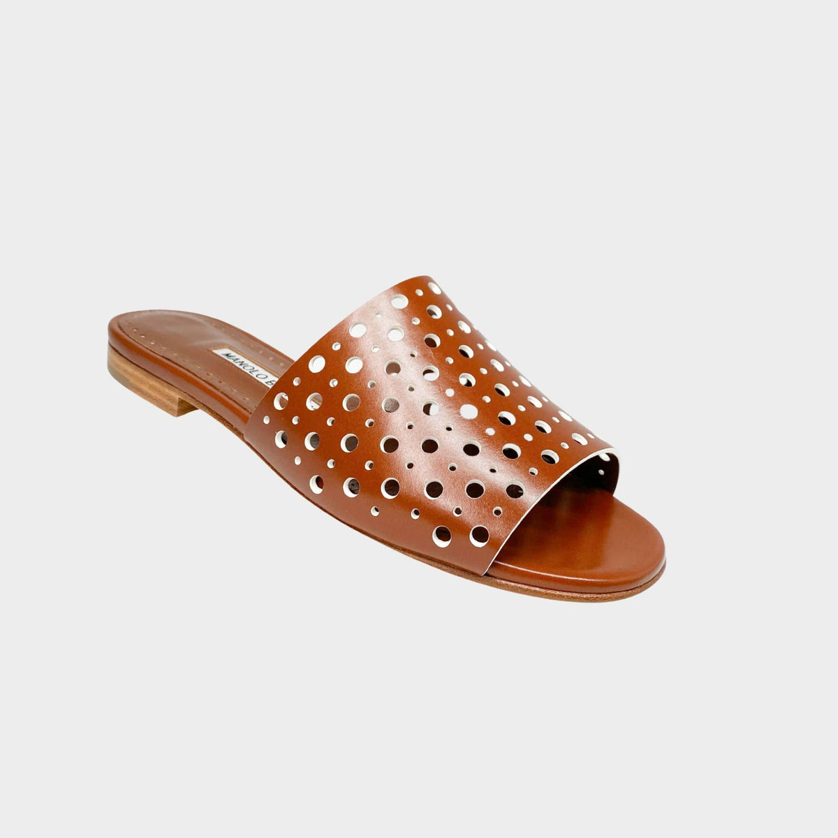 Side profile view of Manolo Blahnik Prepona tan brown leather slide sandals featuring laser-cut perforated straps and low stacked flat heel.