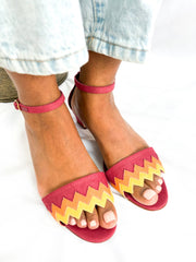 On-foot direct front view of Manolo Blahnik Lochpri red canvas zig-zag sandals styled with light wash cuffed denim jeans.