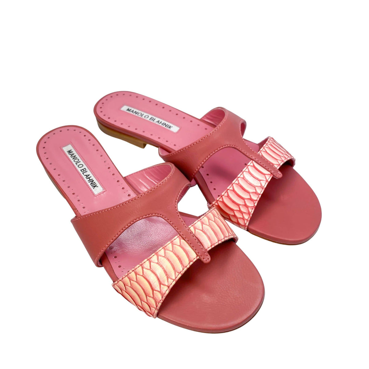 Three-quarter studio view of a pair of Manolo Blahnik Popilla pink leather flat sandals displaying the two-tone woven leather vamp strap.