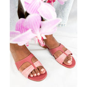 On-foot perspective of Manolo Blahnik Popilla pink leather flat slides styled outdoors among pink florals.