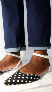 Close-up of a person styling Manolo Blahnik black and white polka dot pointed flats with denim.