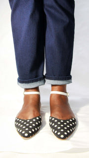 Top-down view of a person wearing Manolo Blahnik Asenso polka dot ankle strap flats with blue jeans.