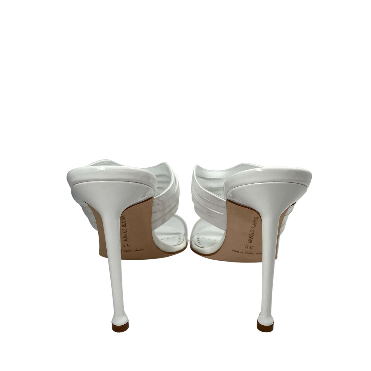 Rear view of a pair of white Manolo Blahnik Curatora sandals highlighting the stiletto heel shape and clean back straps.