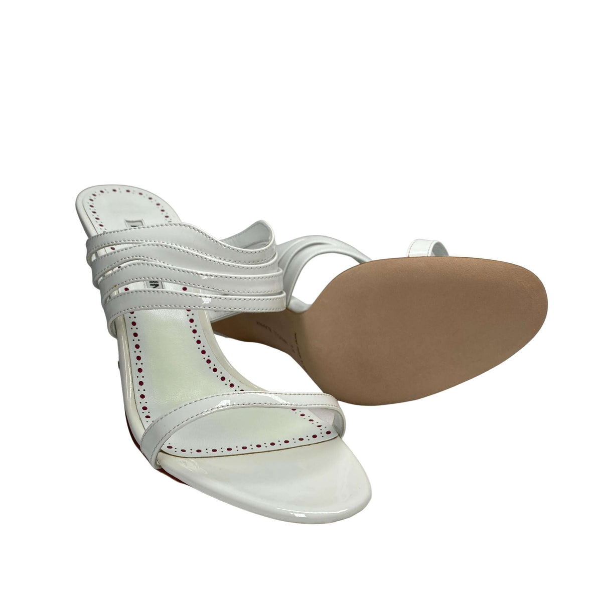 Angled studio view of the Manolo Blahnik Curatora white sandal showcasing the beige leather sole and high heel profile.